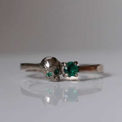 14ct white gold engagement ring with skull and emerald claw set stone. Handmade in London by Charlie Shires
