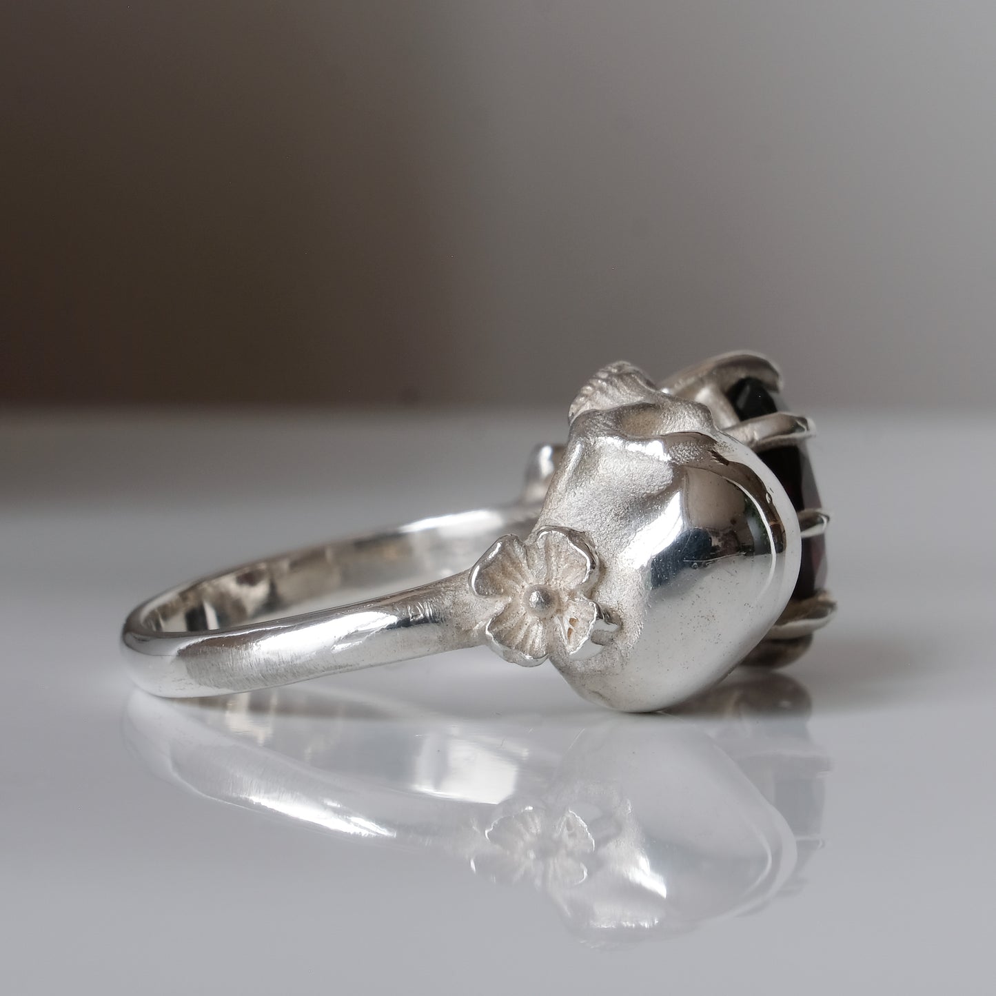 Silver skull and garnet ring with decorative flowers by Charlie Shires jewellery