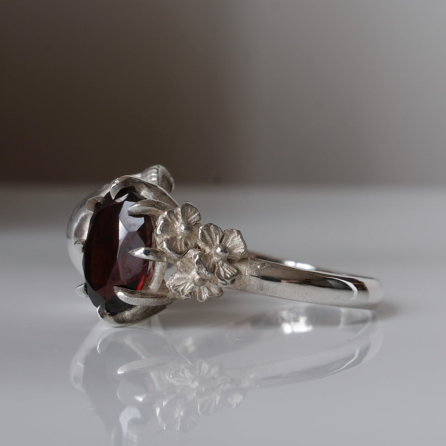 Silver skull and garnet ring with decorative flowers by Charlie Shires jewellery
