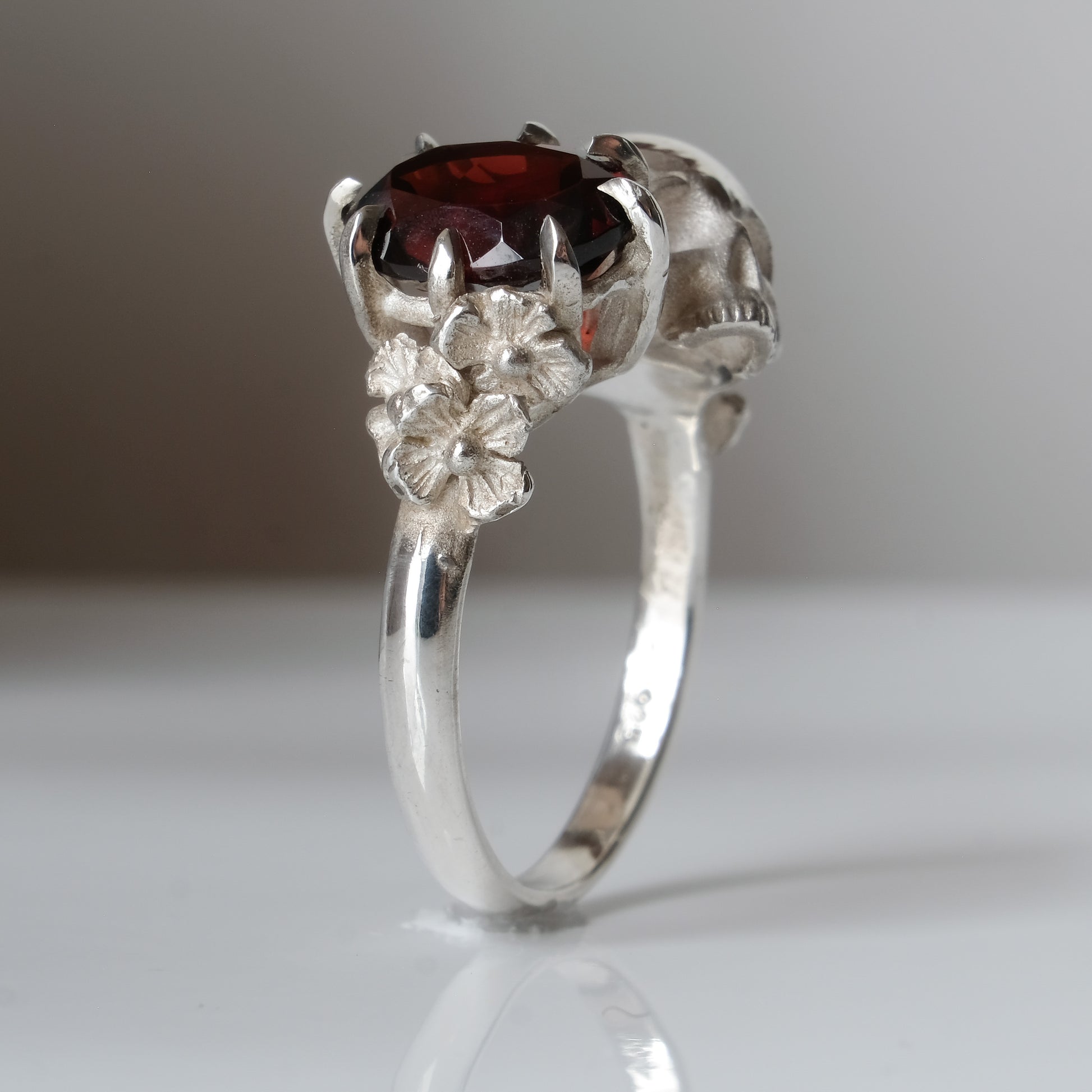 Silver skull and garnet ring with decorative flowers by Charlie Shires jewellery