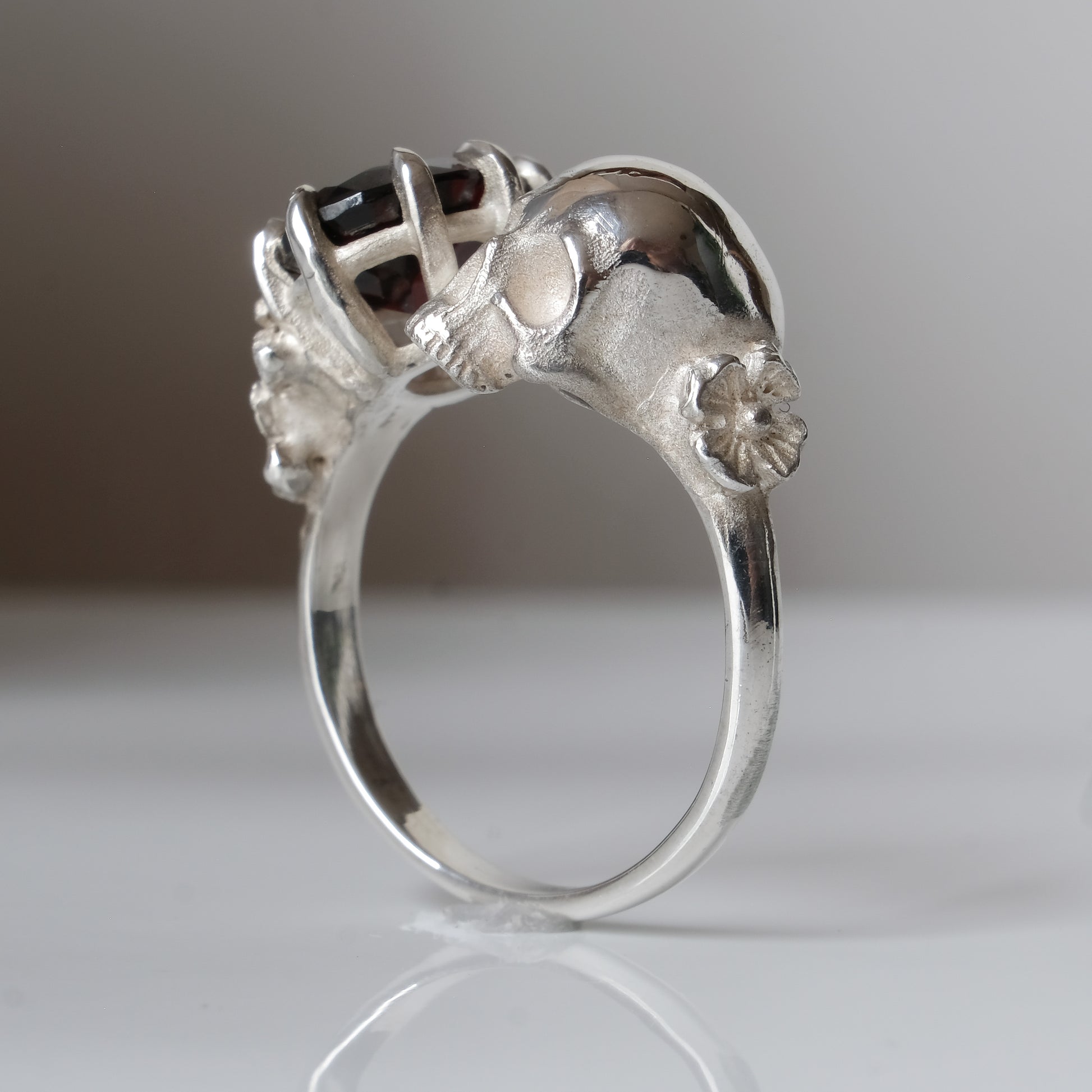 Silver skull and garnet ring with decorative flowers by Charlie Shires jewellery