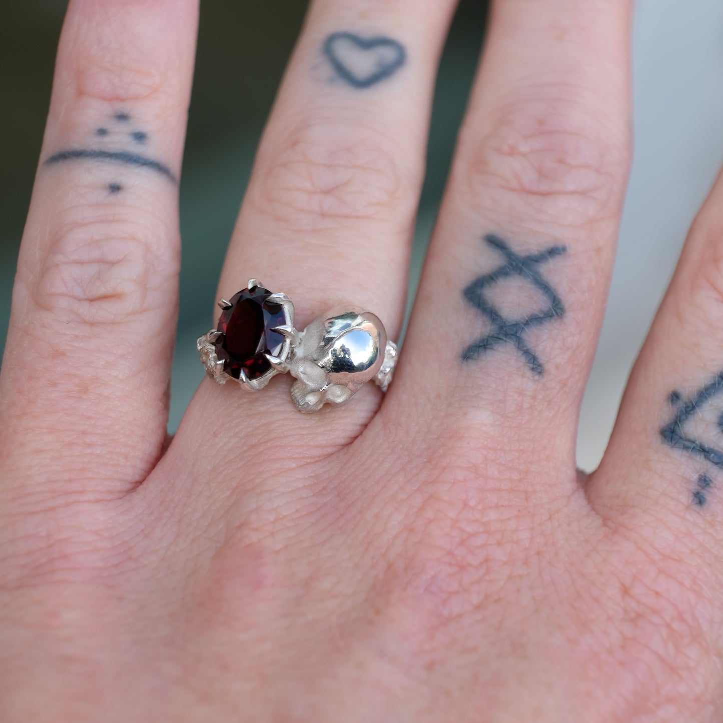 Silver skull and garnet ring with decorative flowers by Charlie Shires jewellery