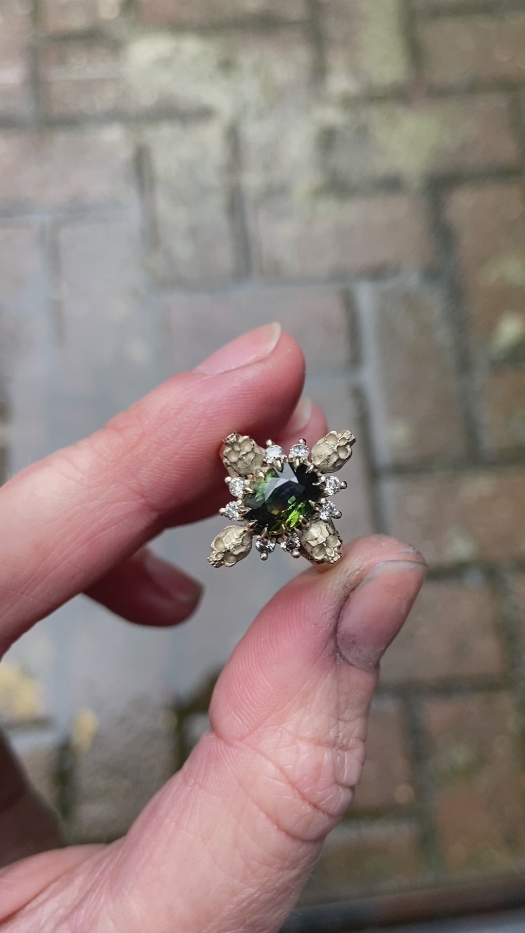 14ct white gold parti sapphire ring with halo of diamonds and skulls. Flowers flank the side of the band. Handmade in London by Charlie Shires